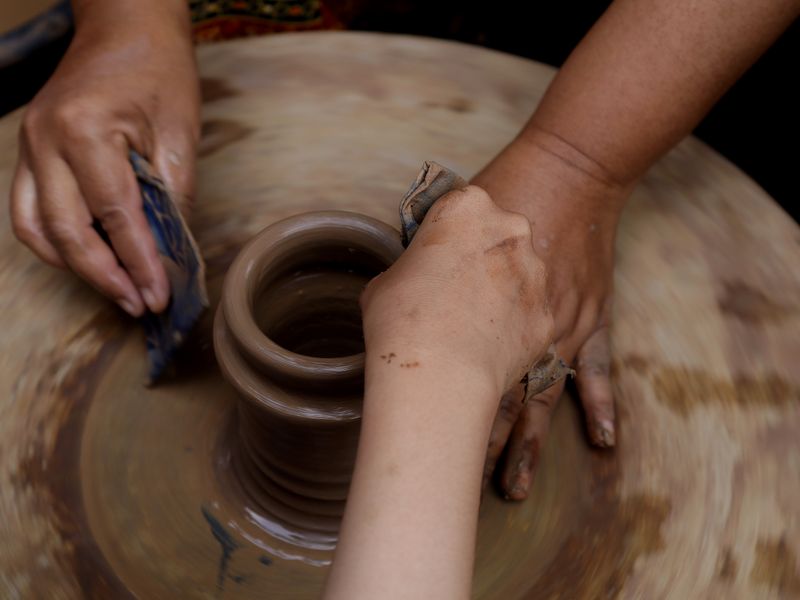 Hands shaping clay on a pottery wheel