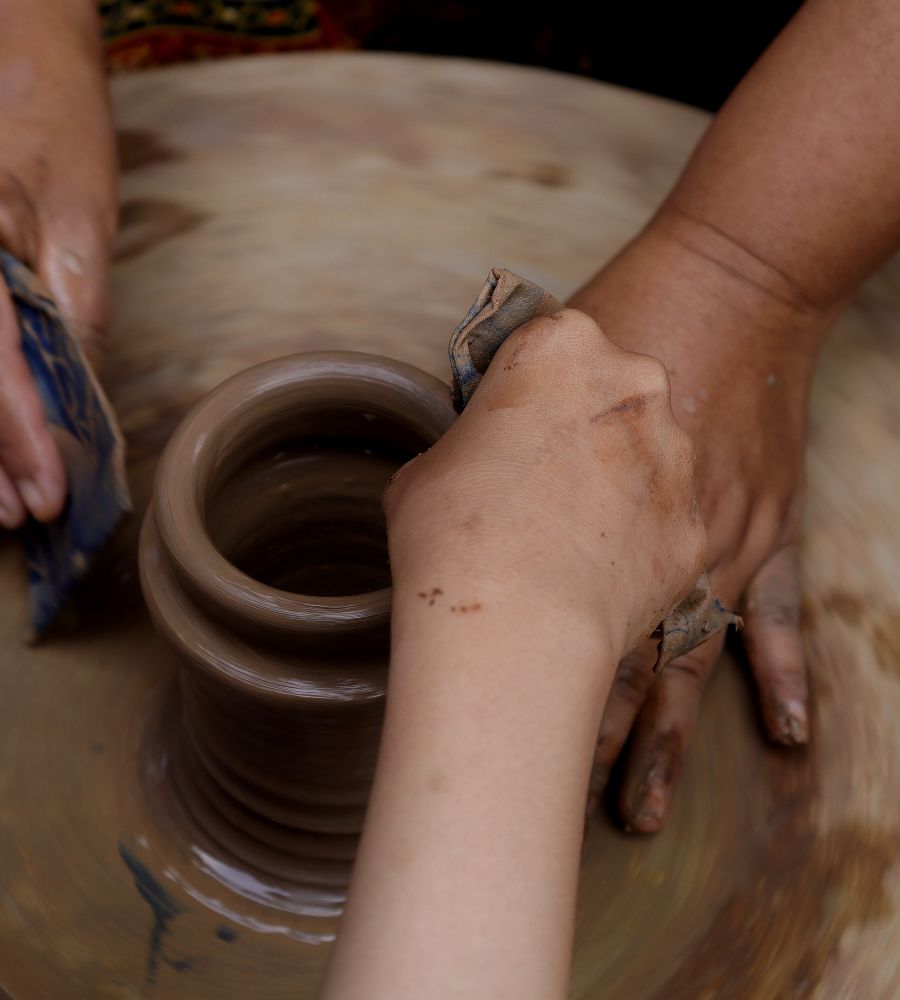 Hands shaping clay on a pottery wheel