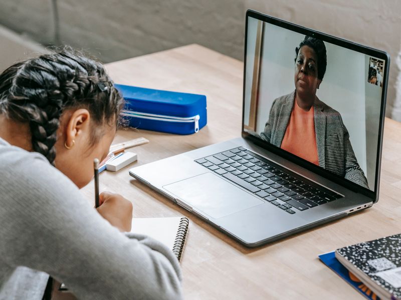 A student taking notes while a teacher teaches over a video call
