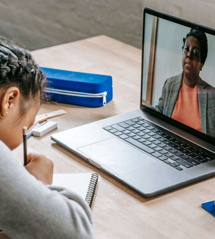A student taking notes while a teacher teaches over a video call