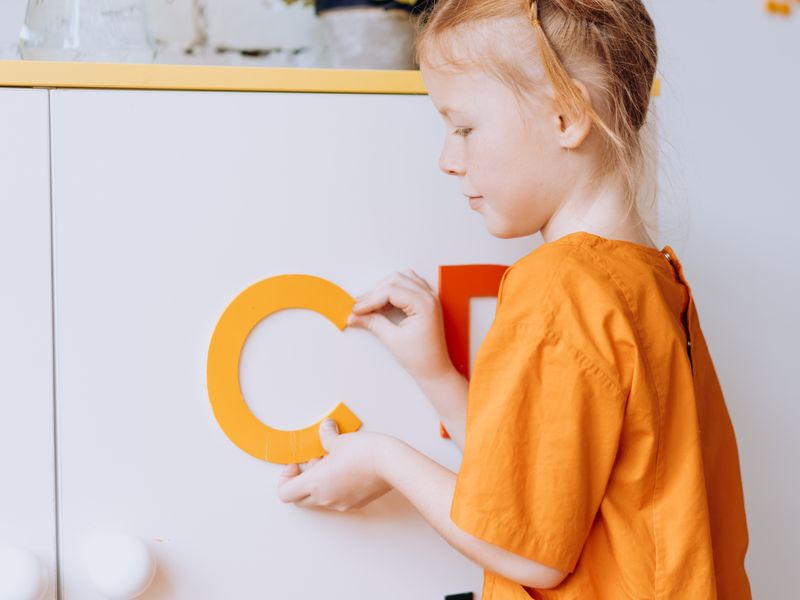 A young learner placing alphabet letters on a whiteboard